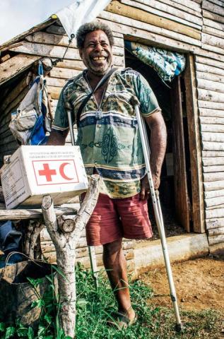 A man with one leg using a crutch, smiling and showing the relief package he received